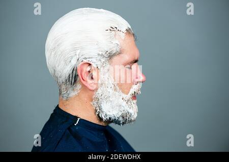 Prozess eines Kerl Haarfarbe beim Friseur. Stylist Mann mit Haarfärbemittel und Pinsel Färbung Haar. Stockfoto