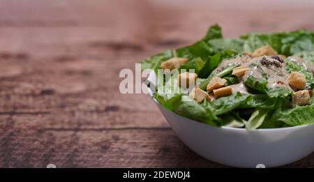 Nahaufnahme des caesar Salats mit Salat, Speck und Croutons auf dem Holztisch. Speicherplatz kopieren. Stockfoto