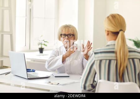 Leitende Ärztin erzählt und erklärt dem Patienten während der Konsultation seine Diagnose. Stockfoto