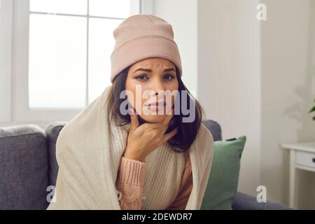 Unglücklich kranke junge Frau in warmer Kleidung, die an Grippe leidet Und sich über Halsschmerzen beklagen Stockfoto