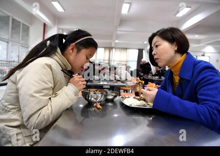 (201202) -- WUHU, 2. Dezember 2020 (Xinhua) -- Xi Weijing, Leiterin der Wuhu Schule für Blinde, iß zusammen mit ihrer Schülerin in der Kantine der Schule in Wuhu, ostchinesische Provinz Anhui, 26. November 2020. XI Weijings Eltern sind beide sehbehindert. Ihr Vater Xi Manqiao hat 1979 eine Privatschule für Blinde eingerichtet und seine ganze Energie der Arbeit der Schule gewidmet. Nachdem ihr Vater 1994 an Krankheit starb, übernahm Xi Weijing, damals 20 Jahre alt, die Last und wurde zum zweiten Direktor der Wuhu Blindenschule. Mit Unterstützung der lokalen Regierung, die Wuhu Schule für Th Stockfoto