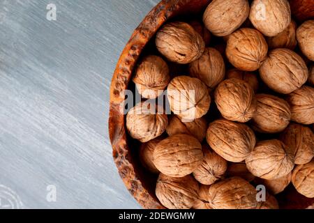 Walnüsse in einer Holzschale aus Grau-Eiche auf einem blauen Tisch Stockfoto