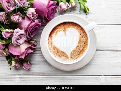 Morgen Tasse Kaffee und schöne Rosenblüten auf einem hellen Hintergrund, Draufsicht. Gemütliches Frühstück. Flach liegend Stockfoto