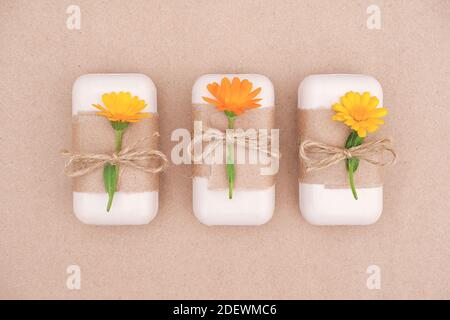 Drei handgemachte Naturseife Set mit Bastelpapier, Geißel und orangen Ringelblumen verziert. Bio-Kosmetik, keine Abfälle, umweltfreundlich Stockfoto
