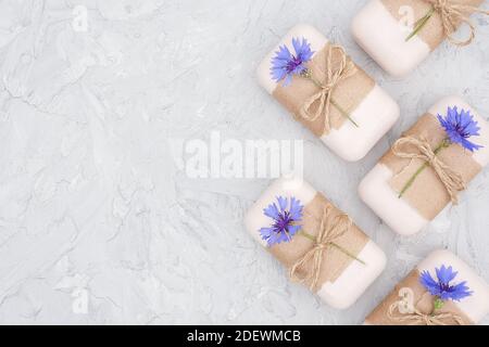 Handgemachte Naturseife Set Grenze mit Bastelpapier, Geißel und blauen Kornblumen auf grauem Stein backgroun dekoriert. Bio-Kosmetik, Null Abfall, Öko Stockfoto