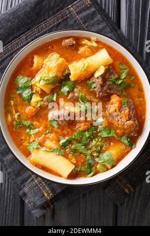 Haitianisches Joumou Rindfleisch und Kürbissuppe in der Nähe in den Teller auf dem Tisch. Vertikale Draufsicht von oben Stockfoto