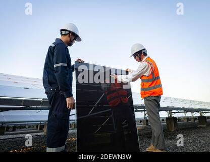 Techniker hebt die Solarzelle, um die beschädigte zu ersetzen, Alternative Energie, um die Energie der Welt zu sparen, Photovoltaikmodul Idee für sauber Stockfoto