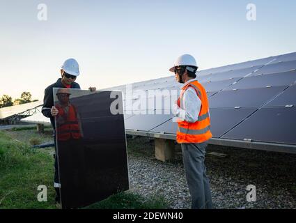 Techniker hebt die Solarzelle, um die beschädigte zu ersetzen, Alternative Energie, um die Energie der Welt zu sparen, Photovoltaikmodul Idee für sauber Stockfoto