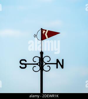 Windfahne mit kleiner Flagge und Nord- und Südindikatoren. Aus schwarzlackiertem Gusseisen. Stockfoto