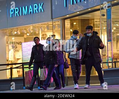 Käufer, die Primark in Birmingham verlassen, als unwesentliche Geschäfte in England öffnen ihre Türen für Kunden zum ersten Mal nach dem zweiten nationalen Lockdown und England hat ein verstärktes System von regionalen Coronavirus-Beschränkungen. Stockfoto