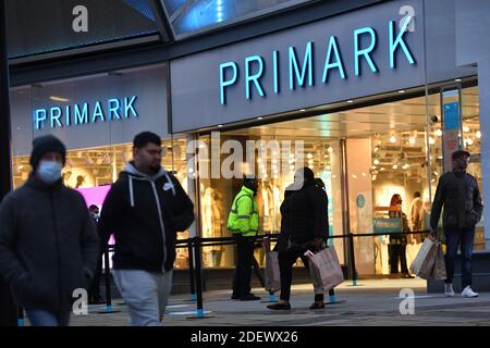 Käufer, die Primark in Birmingham verlassen, als unwesentliche Geschäfte in England öffnen ihre Türen für Kunden zum ersten Mal nach dem zweiten nationalen Lockdown und England hat ein verstärktes System von regionalen Coronavirus-Beschränkungen. Stockfoto