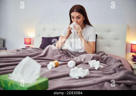 Kranke Frau, die ihre Nase in ein Gewebe bläst Stockfoto