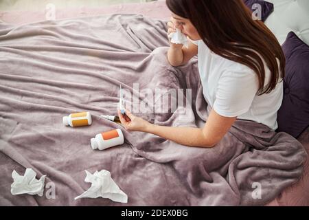 Person, die die Ergebnisse mit einem elektronischen Thermometer überprüft Stockfoto