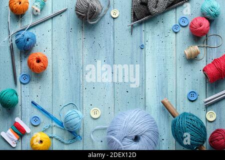 Wollbündel, Garnkugeln, Kordel. Häkel- und Stricknadeln auf hellem mintblauem Holz, Kopierraum Stockfoto