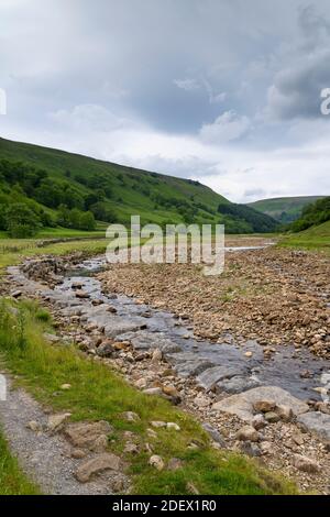 River Swale in landschaftlich reizvollen Tal (niedrige seichte Wasserkanal im trockenen Sommerwetter & Flussbett Felsen) - Swaledale, Yorkshire Dales, England, UK. Stockfoto