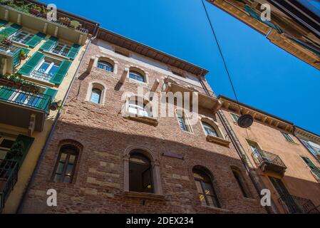 VERONA, ITALIEN - 18. Aug 2020: Blick von einer engen Gasse eines historischen Hauses nach oben in den Himmel mit antiken restaurierten Häusern aus Ziegel, Metall und w Stockfoto