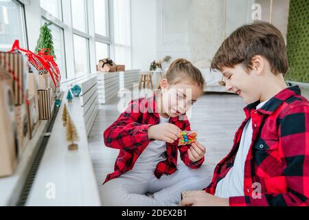 Junge und Mädchen Eröffnung Weihnachten handgemachte Adventskalender mit Süßigkeiten in einem Haus Form, um die Tage bis Weihnachten im Zimmer Countdown. Stockfoto