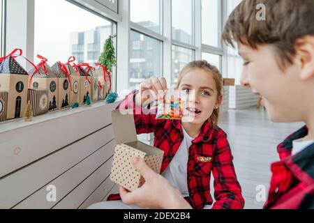 Junge und Mädchen Eröffnung Weihnachten handgemachte Adventskalender mit Süßigkeiten in einem Haus Form, um die Tage bis Weihnachten im Zimmer Countdown. Stockfoto