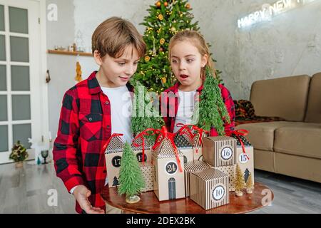 Kinder öffnen Weihnachten handgefertigten Adventskalender in einer Hausform, um die Tage bis Weihnachten im Zimmer Countdown. Stockfoto