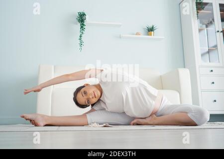 Schöne schwangere Frau, die beim Sitzen in Lotusposition trainiert. Übungen vor der Geburt. Stockfoto