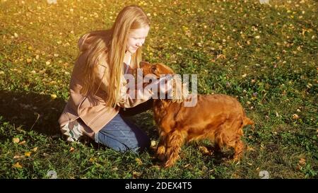 Teenager-Mädchen mit langen losen faires Haar Haustiere genießt Zeit Sitzen auf grünem Gras unter hellem Herbstsonnenlicht Nahaufnahme Stockfoto