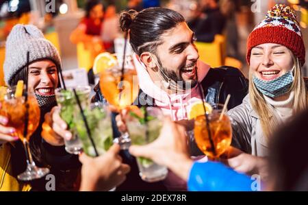 Ein glücklicher Freund hat an der Nachtbar, die geöffnet hat, schicke Getränke getoastet Maske - Neue normale Lifestyle-Konzept mit milenial Menschen mit Spaß zusammen im Winter Stockfoto