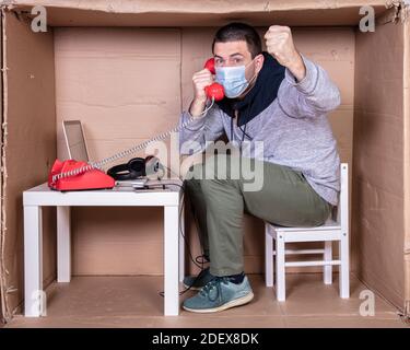 Der Mitarbeiter arbeitet aus seinem eigenen Kartonbüro, um sich zu isolieren Von anderen Stockfoto