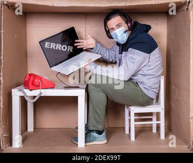 Der Mitarbeiter arbeitet aus seinem eigenen Kartonbüro, um sich zu isolieren Von anderen Stockfoto