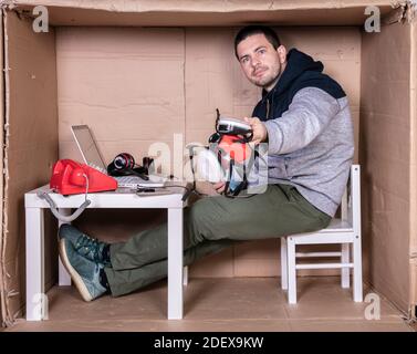 Der Mitarbeiter arbeitet aus seinem eigenen Kartonbüro, um sich zu isolieren Von anderen Stockfoto