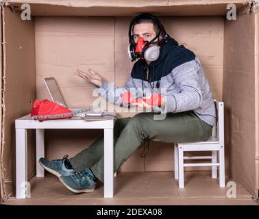 Der Mitarbeiter arbeitet aus seinem eigenen Kartonbüro, um sich zu isolieren Von anderen Stockfoto