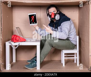 Der Mitarbeiter arbeitet aus seinem eigenen Kartonbüro, um sich zu isolieren Von anderen Stockfoto