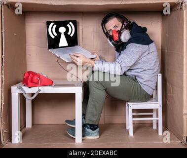 Der Mitarbeiter arbeitet aus seinem eigenen Kartonbüro, um sich zu isolieren Von anderen Stockfoto