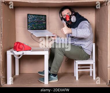 Der Mitarbeiter arbeitet aus seinem eigenen Kartonbüro, um sich zu isolieren Von anderen Stockfoto