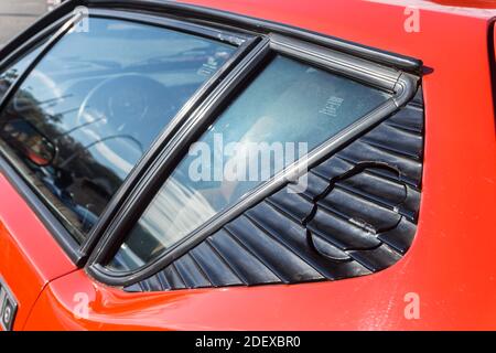 Nahaufnahme der Fenster auf der linken Seite eines roten De Tomaso Pantera GT5-S draußen bei Sonnenschein. Stockfoto