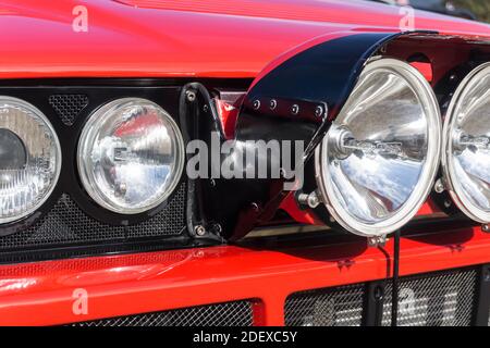 Nahaufnahme der Scheinwerfer und Rally Light Pod Auf einem roten Lancia Delta HF integrale Evoluzione außen Bei Sonnenschein Stockfoto