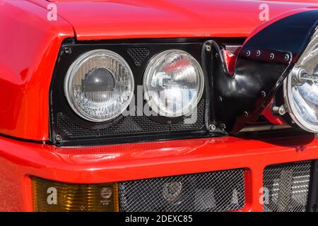 Nahaufnahme der Scheinwerfer und Rally Light Pod Auf einem roten Lancia Delta HF integrale Evoluzione außen Bei Sonnenschein Stockfoto