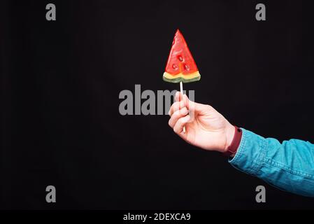 Sommerstimmung mit einem Glas Wassermelone Kerzenständer von einem Mann auf schwarzem Hintergrund gehalten. Stockfoto