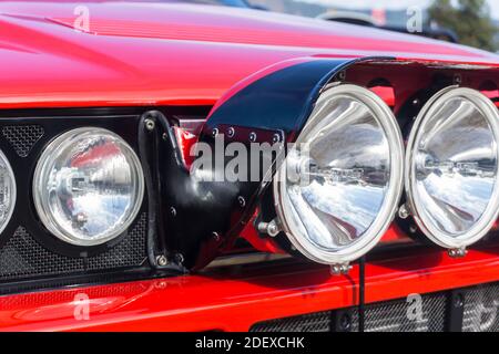 Nahaufnahme der Scheinwerfer und Rally Light Pod Auf einem roten Lancia Delta HF integrale Evoluzione außen Bei Sonnenschein Stockfoto