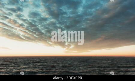 Spektakulärer Himmel über dem Markermeer bei Sonnenaufgang in den Niederlanden Mit einer Reihe von Windmühlen am Horizont und die Städte Amsterdam und Almere Stockfoto