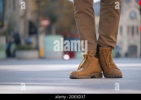 Nicht erkennbarer Mann, der im Stadtzentrum steht. Panoramabild Nahaufnahme der gelben Winterstiefel. Street Photography Dezember 2020. Stockfoto