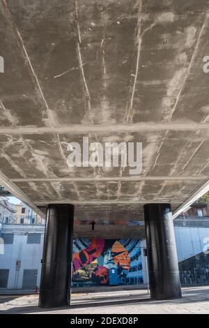 Blick unter einer Fußgängerbrücke mit großen schwarzen Säulen in der Nähe des öffentlichen Bahnhofs Parma, Italien: Keine Menschen. Stockfoto