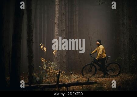 Schöner junger Mann, der beim Radfahren durch den Herbst eine Bremse zieht Wald Stockfoto