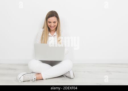 Junge blonde Frau, die mit einem Computer arbeitet Stockfoto