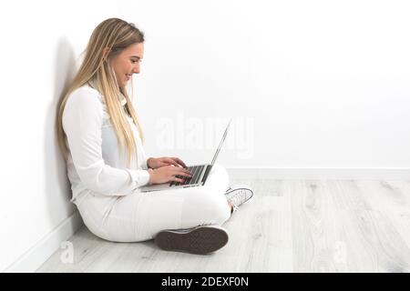 Junge blonde Frau, die mit einem Computer arbeitet Stockfoto