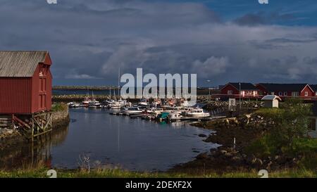 Blick auf den Hafen des Fischerdorfes Andenes im Norden der Insel Andøya, Vesterålen, Norwegen mit Anlegebooten, Wellenbrechern und typischen roten Häusern. Stockfoto