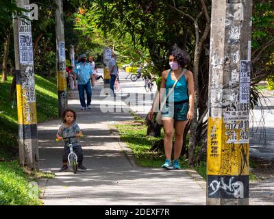 MEDELLIN, KOLUMBIEN - 16. Nov 2020: Medellin, Antioquia / Kolumbien - 15 2020. November: Little Boy fährt ein kleines Fahrrad neben ihrer Mutter auf dem Bürgersteig Stockfoto