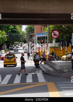 MEDELLIN, KOLUMBIEN - 16. Nov 2020: Medellin, Antioquia / Kolumbien - 15 2020. November: Männlicher Passant mit Gesichtsmaske überqueren die Straße unter einem Beton S Stockfoto