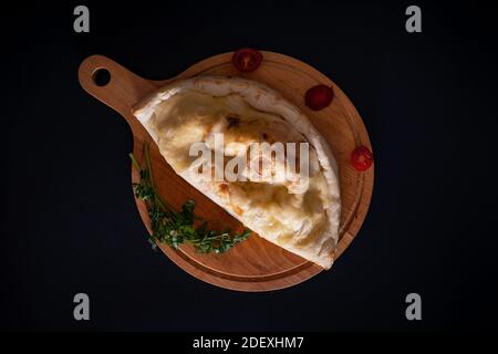 Ein Blick von oben auf ein frisch gebackenes Gebäck mit überzogen Geschmolzener Käse auf einem Holztablett Stockfoto