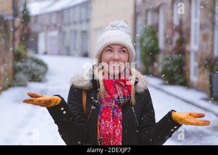 Eine junge Frau freut sich über einen sanften Schneefall in Edinburgh, Schottland Stockfoto