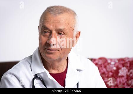 Ein Porträt eines Arztes, der zu einem Anruf bei einer älteren Frau kam. Foto des Hauses auf der Couch. Stockfoto